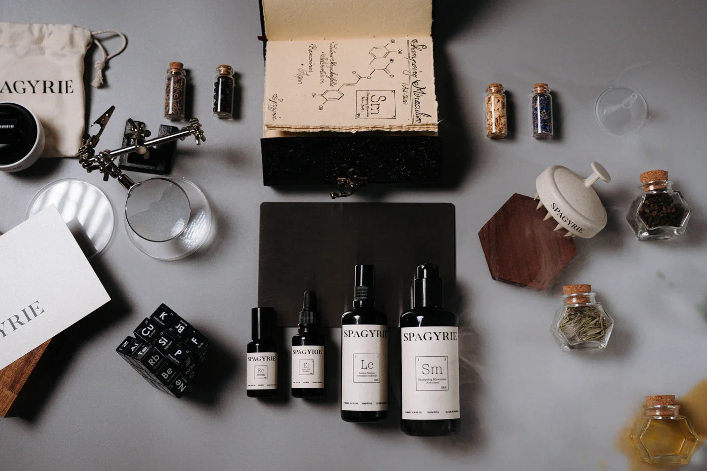 Produits botaniques SPAGYRIE à base d’ingrédients naturels pour stimuler la pousse des cheveux chez l’homme, présentés avec herbes et fioles artisanales